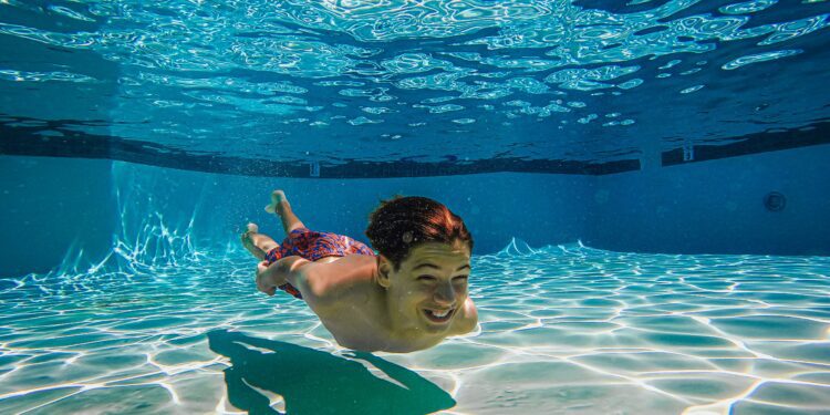 Shirtless kid swimming under water